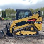 CAT 259D compact track loader with front bucket at a Heavy Iron Inc. equipment yard.